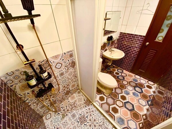 Un baño con baldosas estampadas, un inodoro, un lavamanos y una zona de ducha.