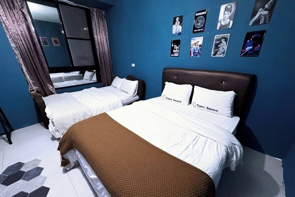 Una habitación de hotel con dos camas, un ventanal con cortinas y una pared decorada con cuadros.