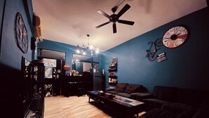 A living room with a ceiling fan, a clock, and a bicycle on the wall. - Kenting Timehouse (Hengchun)