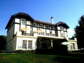 Un edificio grande de dos pisos con un balcón y sombrillas exteriores.