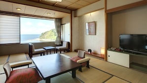 A traditional Japanese room with tatami flooring, a low table, chairs, a television, and a view of the sea. - Wajimaonsen Yashio (Wajima)
