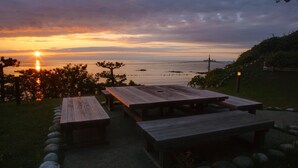 A sunset view with wooden picnic tables and a stone pathway. - Wajimaonsen Yashio (Wajima)