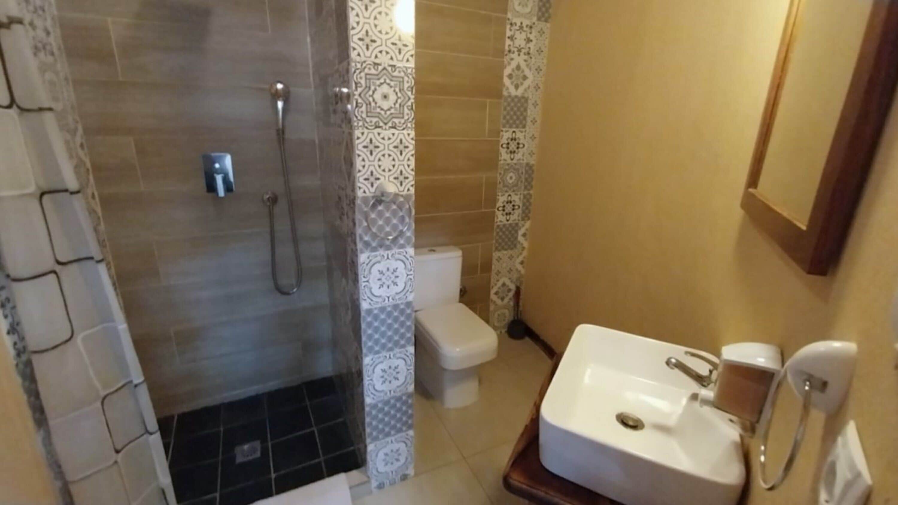A bathroom with a shower, toilet, and sink.