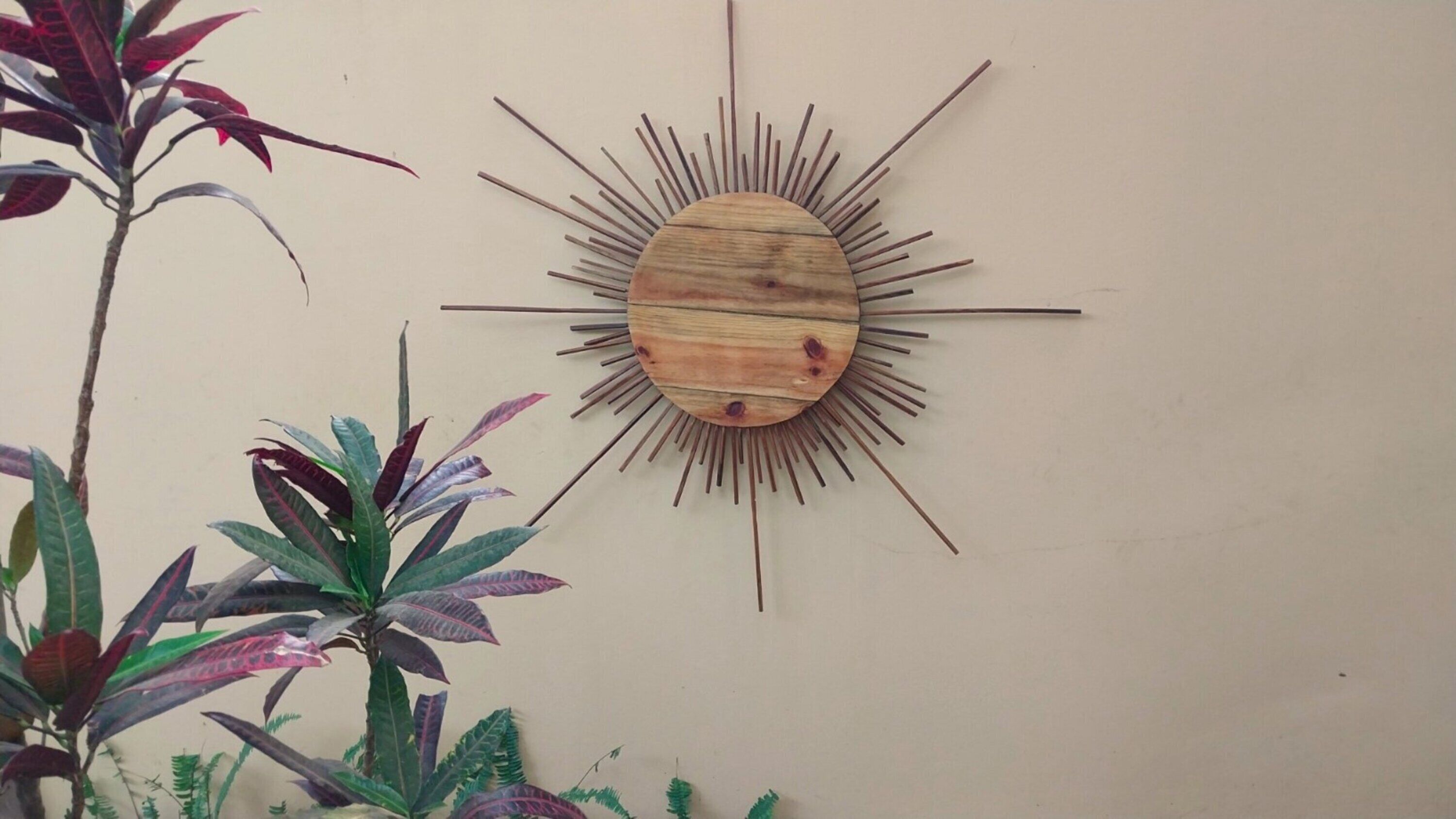 Decoración de madera para pared con forma de sol, con un centro circular y listones de madera que irradian desde él.