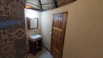 Casa de banho com lavatório, espelho e porta de madeira.