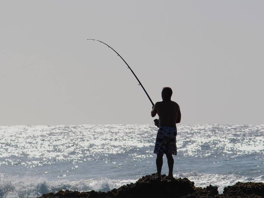 Una persona pescando junto al mar.
