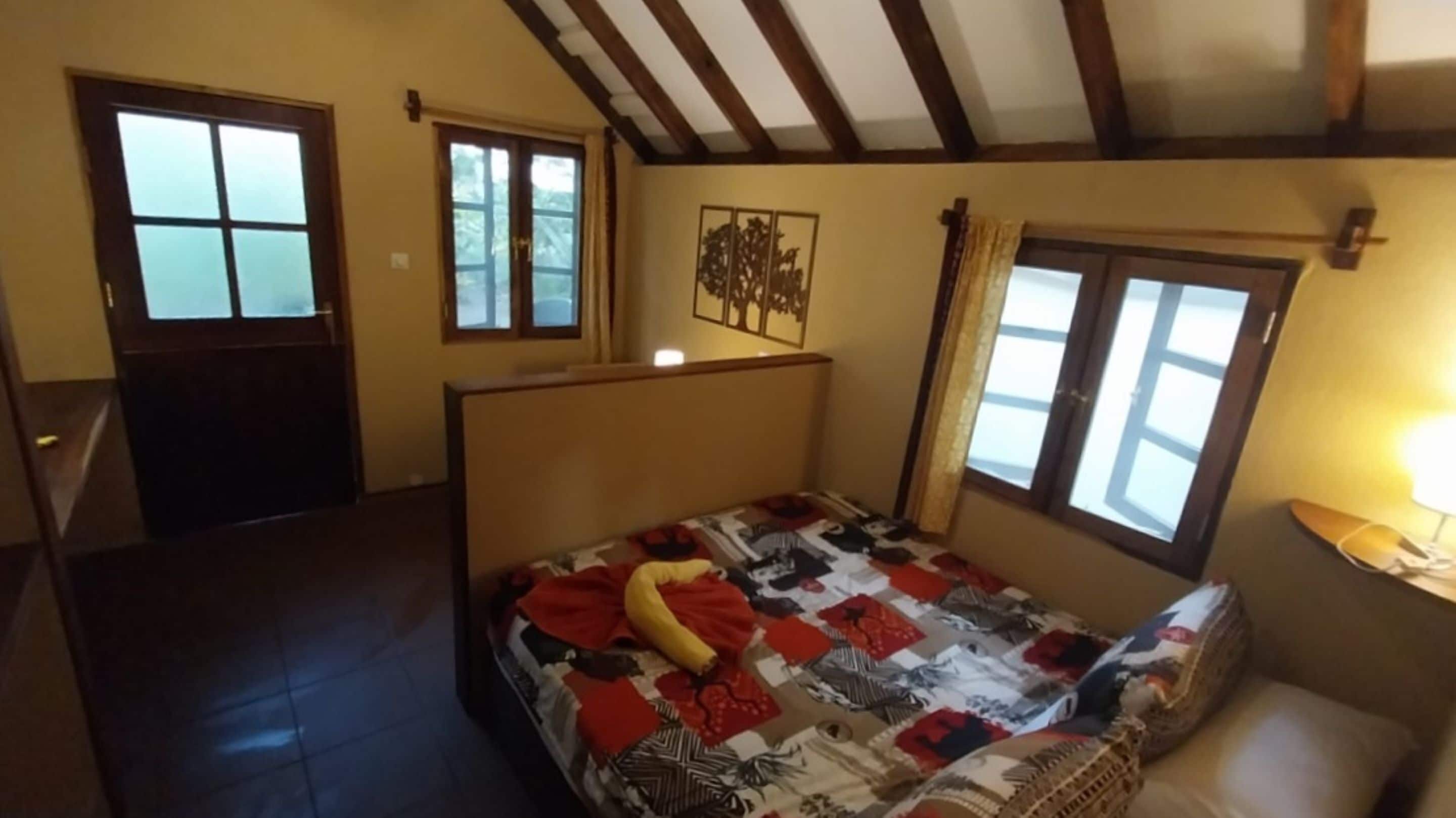 Un dormitorio con cama, ventana, puerta y un cuadro colgado en la pared.