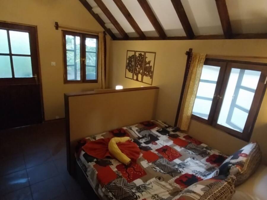 A bedroom with a bed, a window, a door, and a wall-mounted picture.