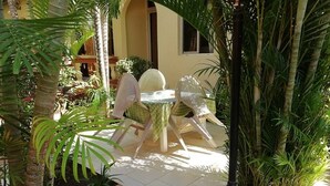 An outdoor seating area with a table and chairs, surrounded by palm trees and plants. - Sermaho Residence - Adults Only (Serrekunda)