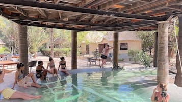 Una piscina al aire libre, una piscina natural, sombrillas