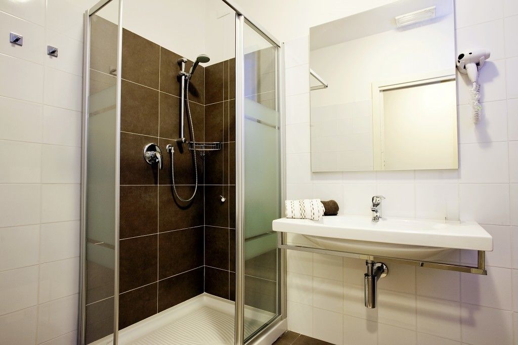 Une salle de bain moderne avec une douche à parois de verre, un lavabo blanc et un miroir au-dessus.