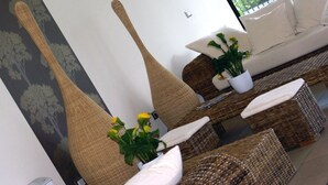 A modern living room with a sofa set, wicker chairs, and a large vase with yellow flowers. - Riviera Palace Residence (Loano)