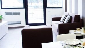 A modern dining area with a table set for two, a sofa, and a potted plant. - Riviera Palace Residence (Loano)