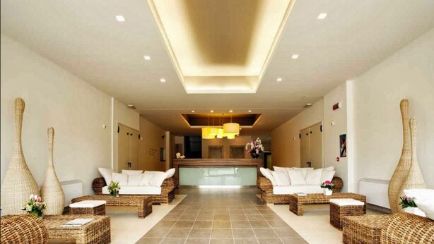 A spacious lobby with a central reception desk, two sofas with white cushions, and decorative vases. - Riviera Palace Residence (Loano)