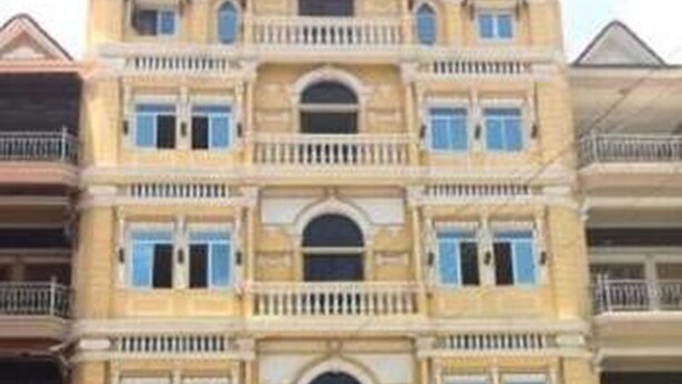 A multi-story building with a symmetrical facade, featuring a central entrance with an arched doorway, multiple balconies, and evenly spaced windows. - Golden World Guesthouse (Phnom Penh)