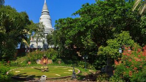 A white pagoda surrounded by lush greenery and a circular garden with a statue in the center. - Golden World Guesthouse (Phnom Penh)