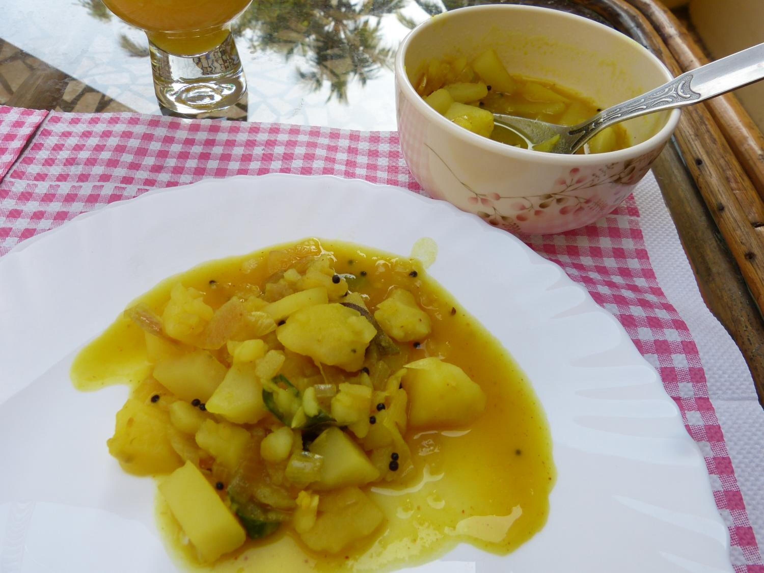 Ein Teller Essen mit einer Schüssel und einem Löffel auf einer karierten Tischdecke.