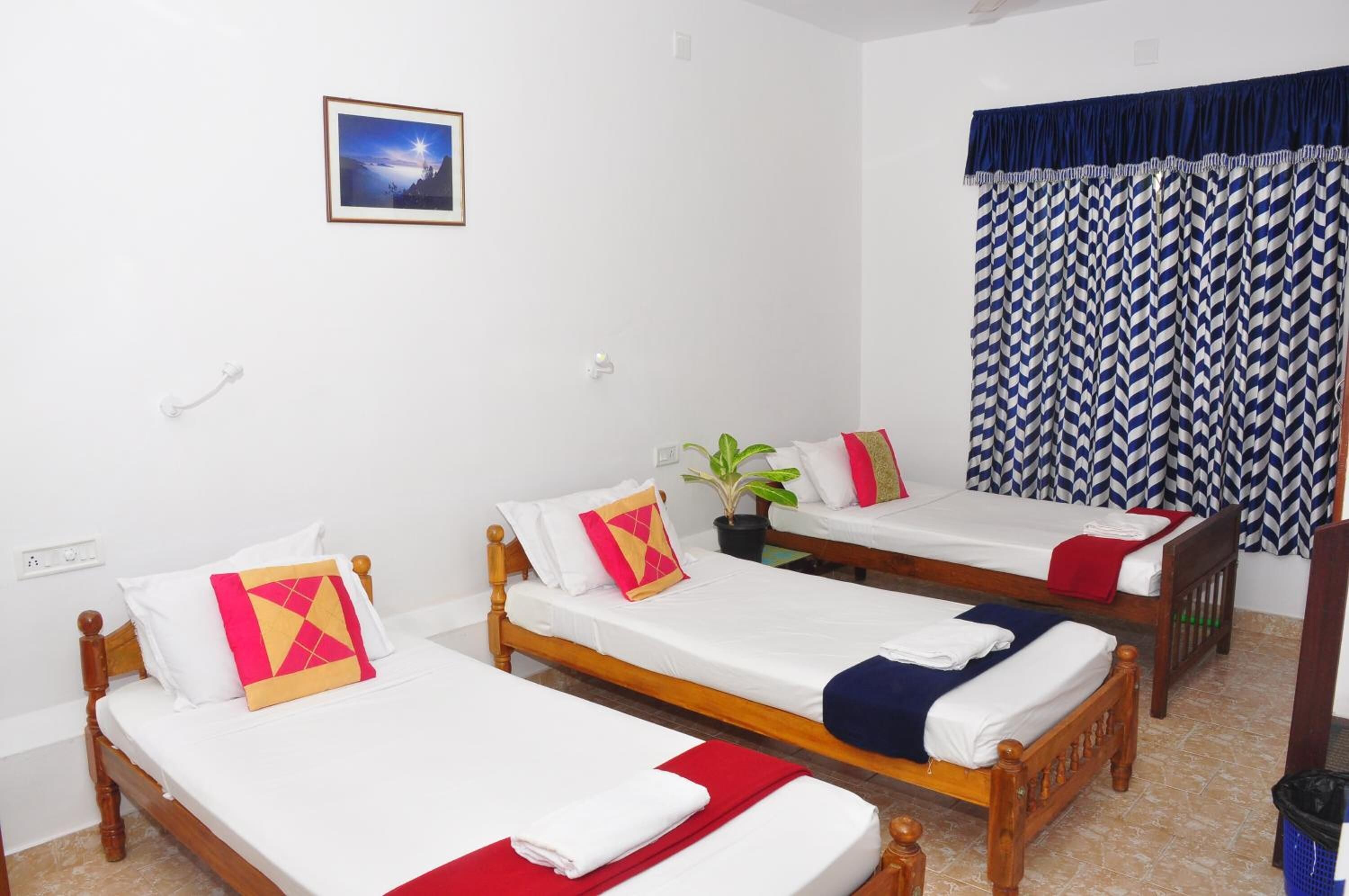 Una habitación con tres camas de madera, ropa de cama blanca y un cuadro en la pared.