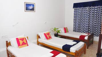 Una habitación con tres camas de madera, ropa de cama blanca y un cuadro en la pared.