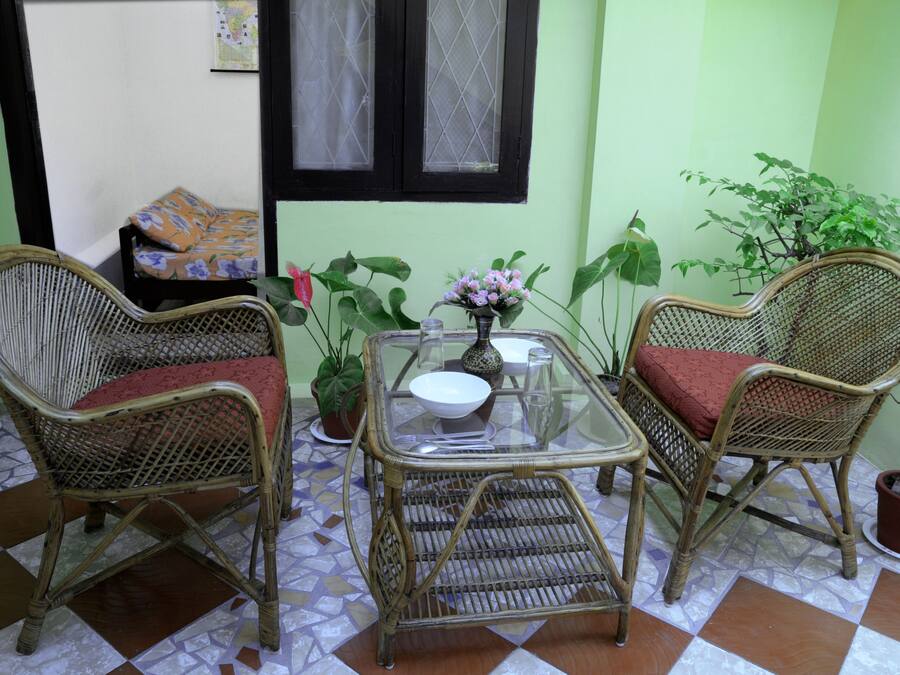 A room with two wicker chairs, a glass table, and potted plants.
