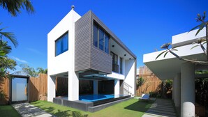 Een modern huis met twee verdiepingen, een zwembad, een houten omheining en een verzorgd gazon.