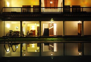 Un edificio de dos pisos con un balcón, una escalera y una piscina.