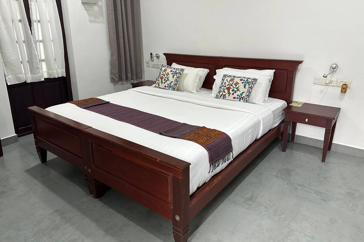 Una cama bien hecha con estructura de madera, una mesita de noche y un velador.