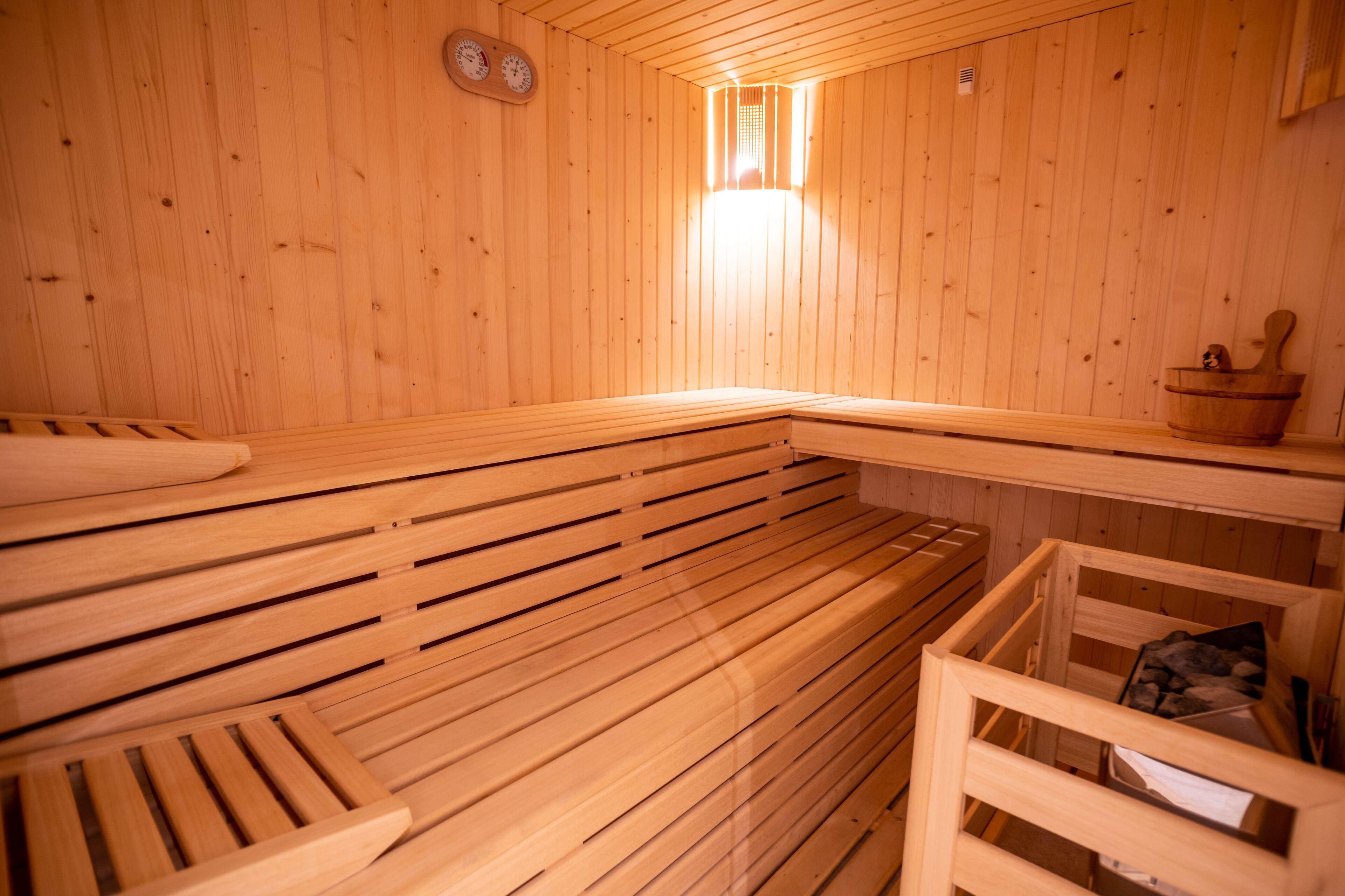 Una sauna de madera con bancos y una pequeña mesa con un cuenco.