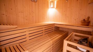 Una sauna de madera con bancos y una pequeña mesa con un cuenco.