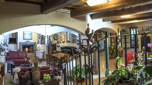 A spacious living area with a fireplace, red leather sofa, wooden dining table, and various decorative items.