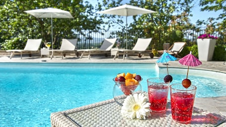 Una piscina al aire libre de temporada, sombrillas