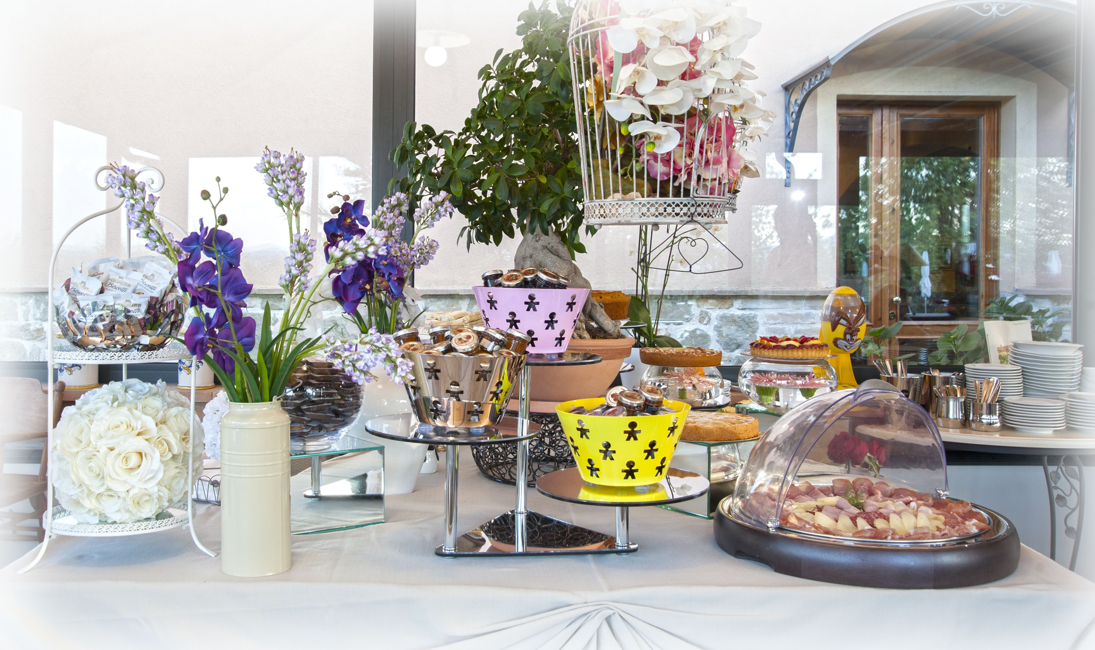 Une table de buffet garnie de divers plats, un vase de fleurs et une cage à oiseaux décorative.