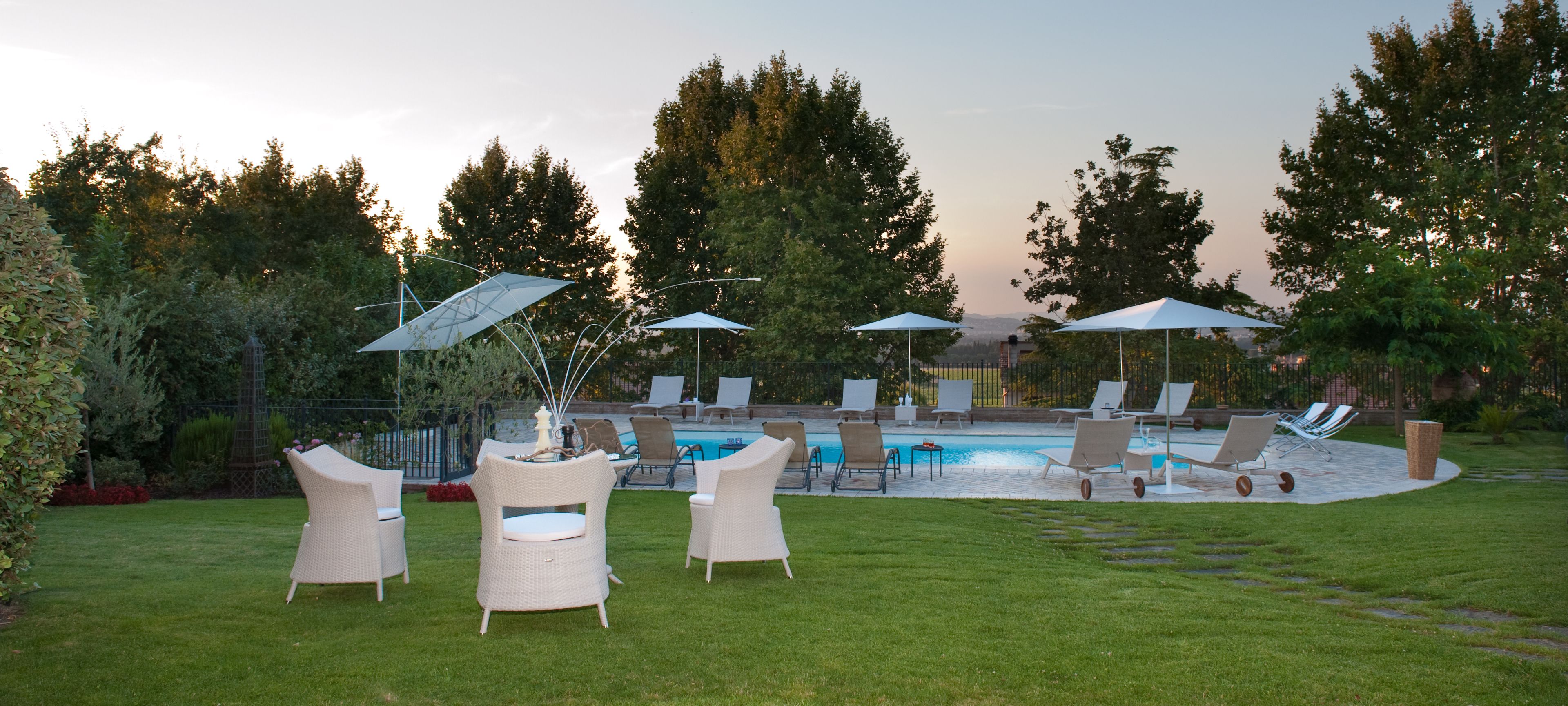 A backyard with a swimming pool, lounge chairs, and umbrellas.