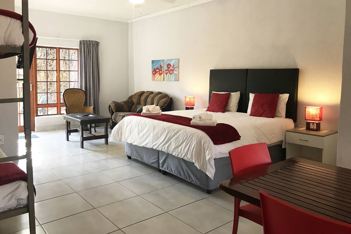 Ein Hotelzimmer mit Bett, Schreibtisch, Stuhl, Fenster und Deckenventilator.
