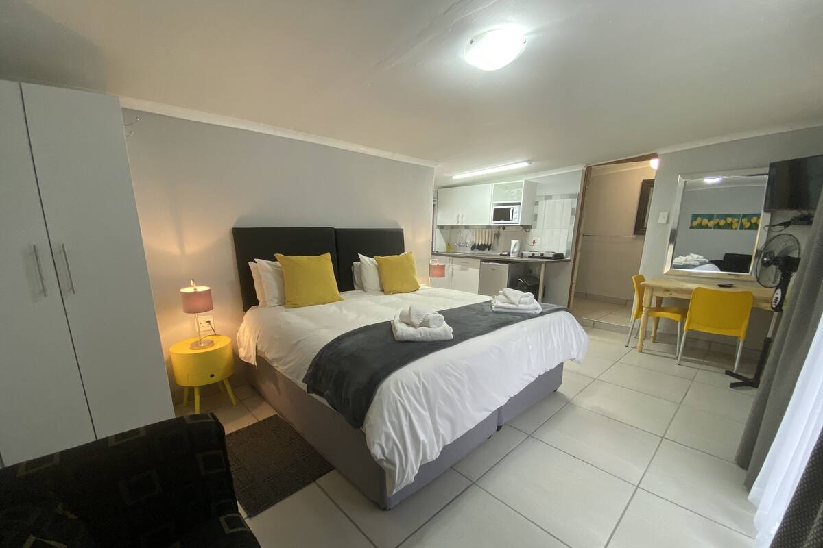 Ein Hotelzimmer mit Bett, Nachttisch, Lampe und einem kleinen Schreibtisch mit Stuhl.
