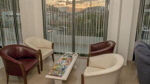 A living room with a sofa, armchairs, and a coffee table with magazines. - Sun Hotel (Cesme)