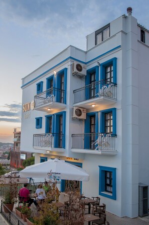Un hotel de varios pisos con balcones, mobiliario exterior y vistas a la ciudad.