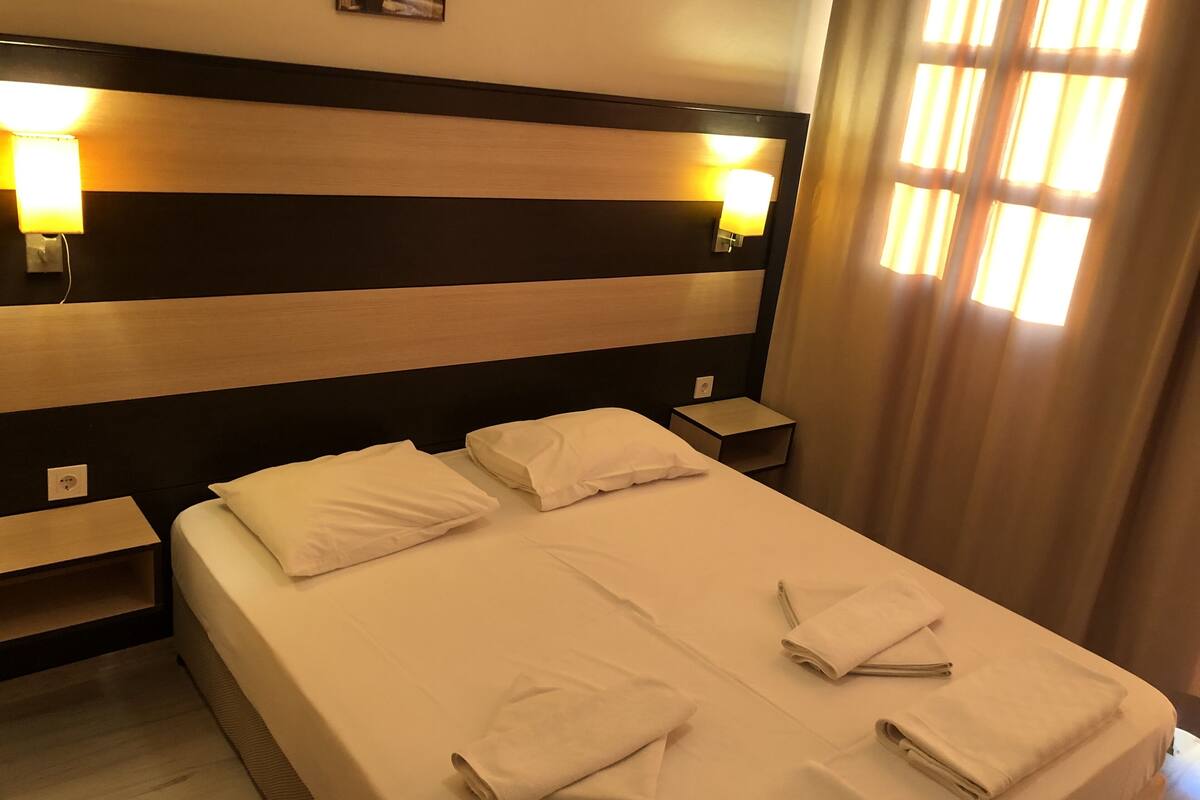 A hotel room with a large bed, two bedside tables, and a headboard with a painting.
