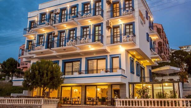 A multi-story hotel with balconies, a restaurant on the ground floor, and a stone facade. - Sun Hotel (Cesme)