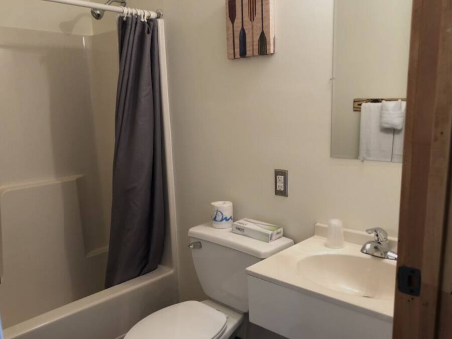 A bathroom with a shower, toilet, sink, and a towel rack.