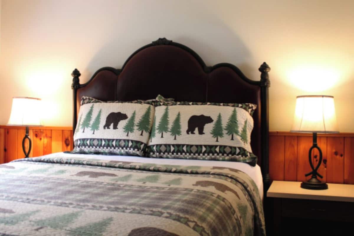 A bed with a headboard, two bedside lamps, and a patterned bedspread.
