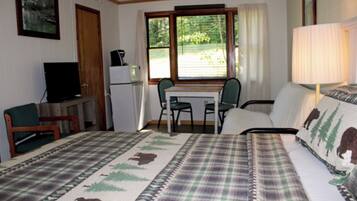 A room with a bed, a desk, a chair, a television, and a lamp.