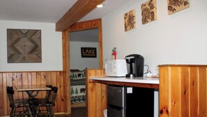 A kitchen with wooden paneling, a dining table with chairs, a refrigerator, a coffee maker, and a sign that reads "LAKE". - Luzerne Court Motel (Lake Luzerne)