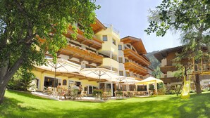 A hotel with outdoor seating, a playground, and a mountain view. - Hotel Pinzger (Tux)