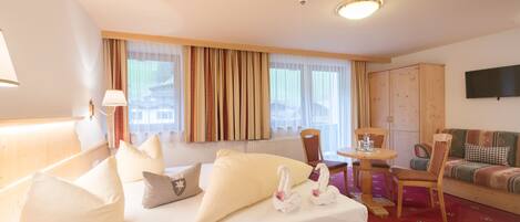 A hotel room with a bed, a desk, a chair, a sofa, and a television.