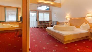 A hotel room with a large bed, a small table, and a window with curtains.