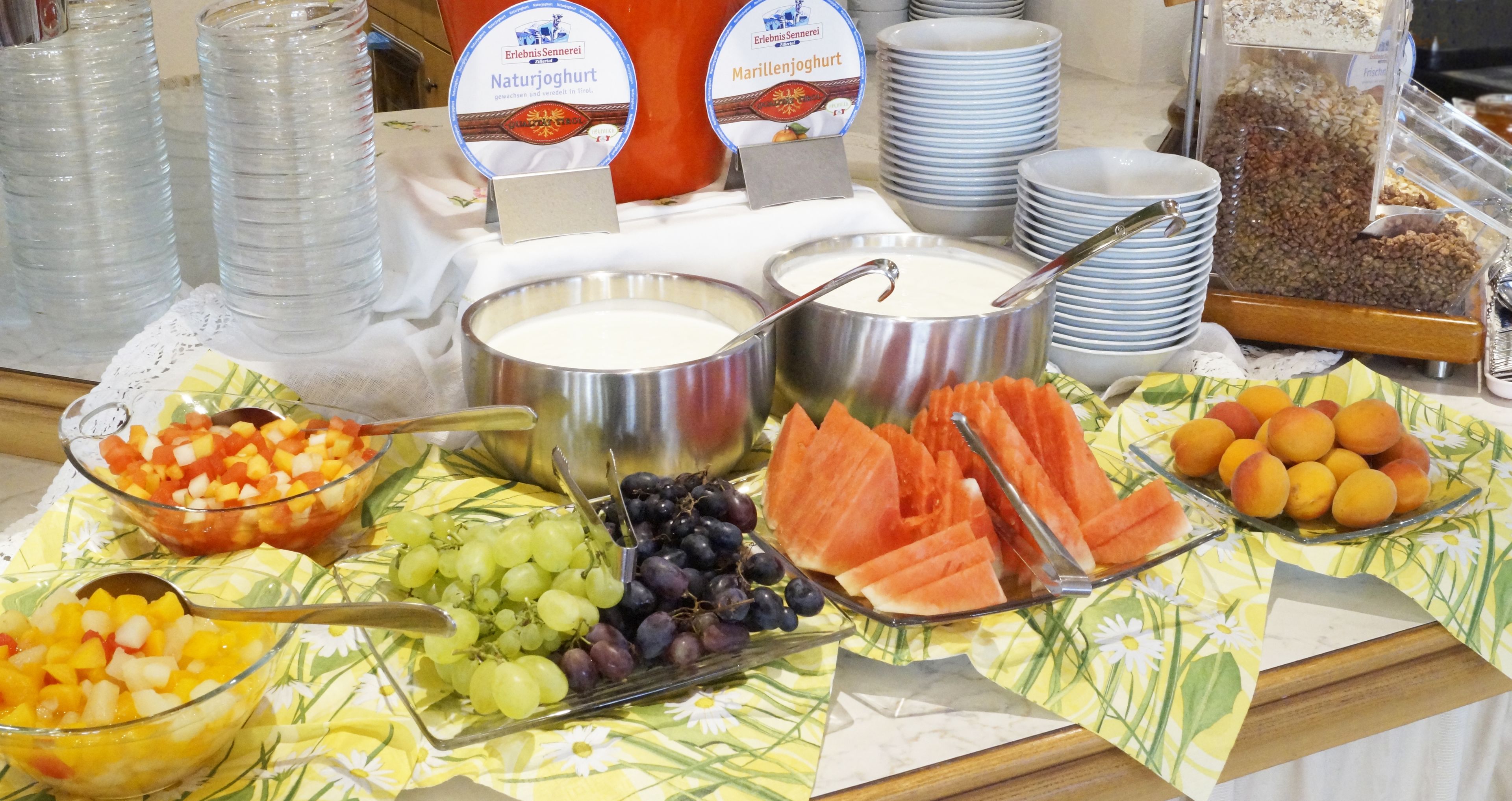Un buffet proposant une variété d’aliments, notamment des fruits, du yaourt et des céréales.