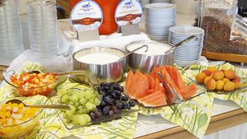 Un buffet proposant une variété d’aliments, notamment des fruits, du yaourt et des céréales.
