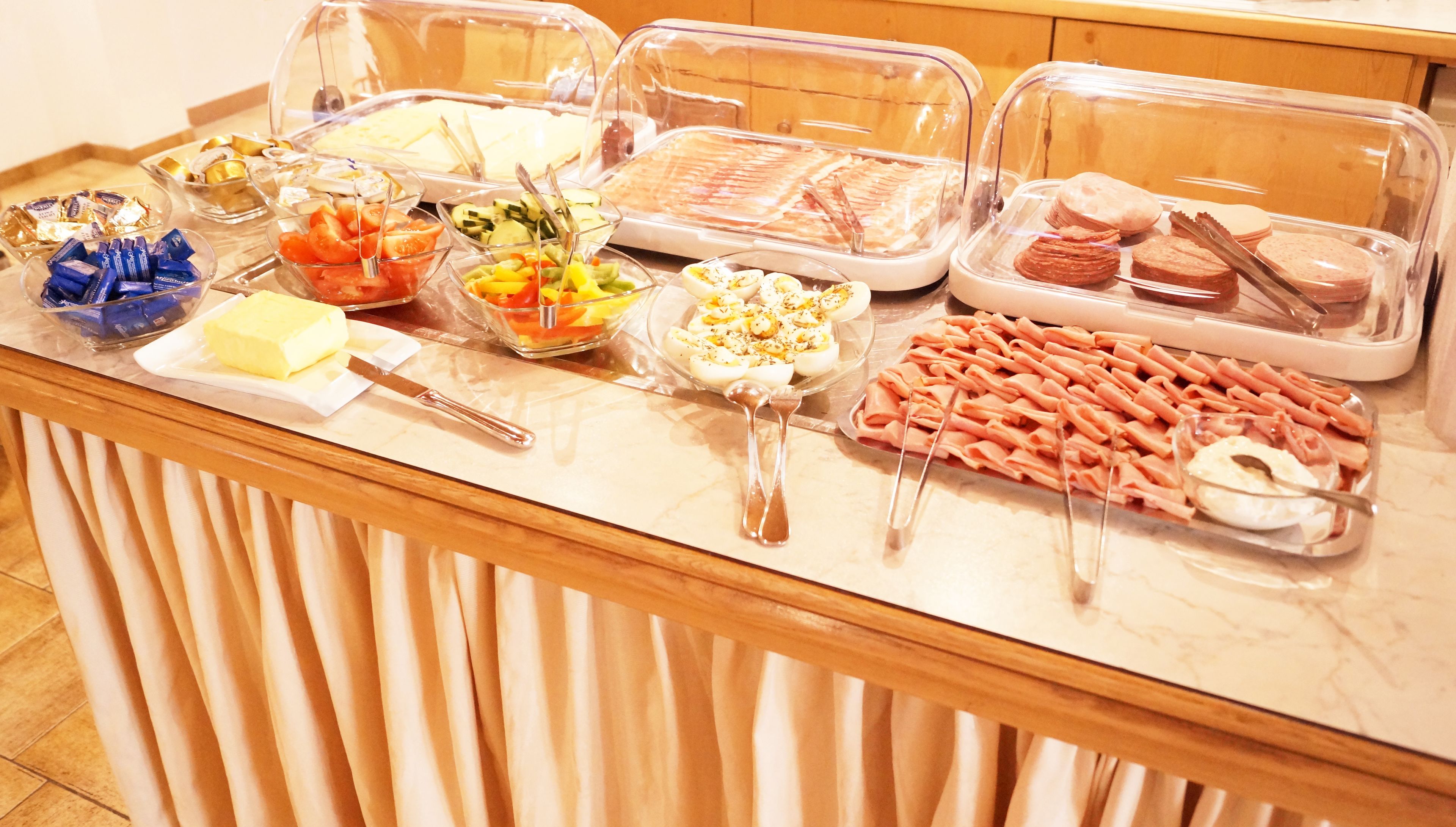 A buffet with various food items including bread, pastries, and a selection of cheeses.