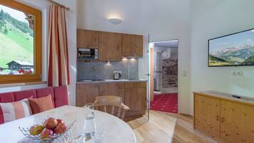 Une cuisine moderne avec des meubles en bois, un four à micro-ondes encastré et une grande fenêtre avec des rideaux.